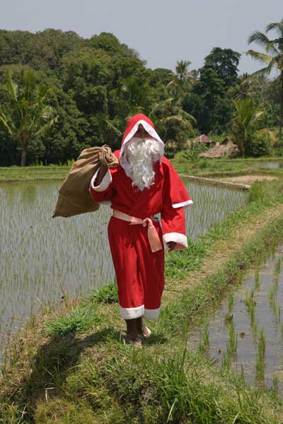 Santa Claus wandert durch die Reisfelder zu einem kleinen Dorf